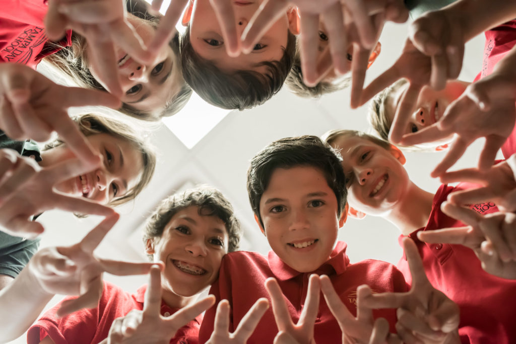 Students in group make formation with fingers as they look into the camera.