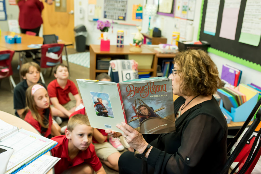 Lower Elementary teacher reads book to small class.