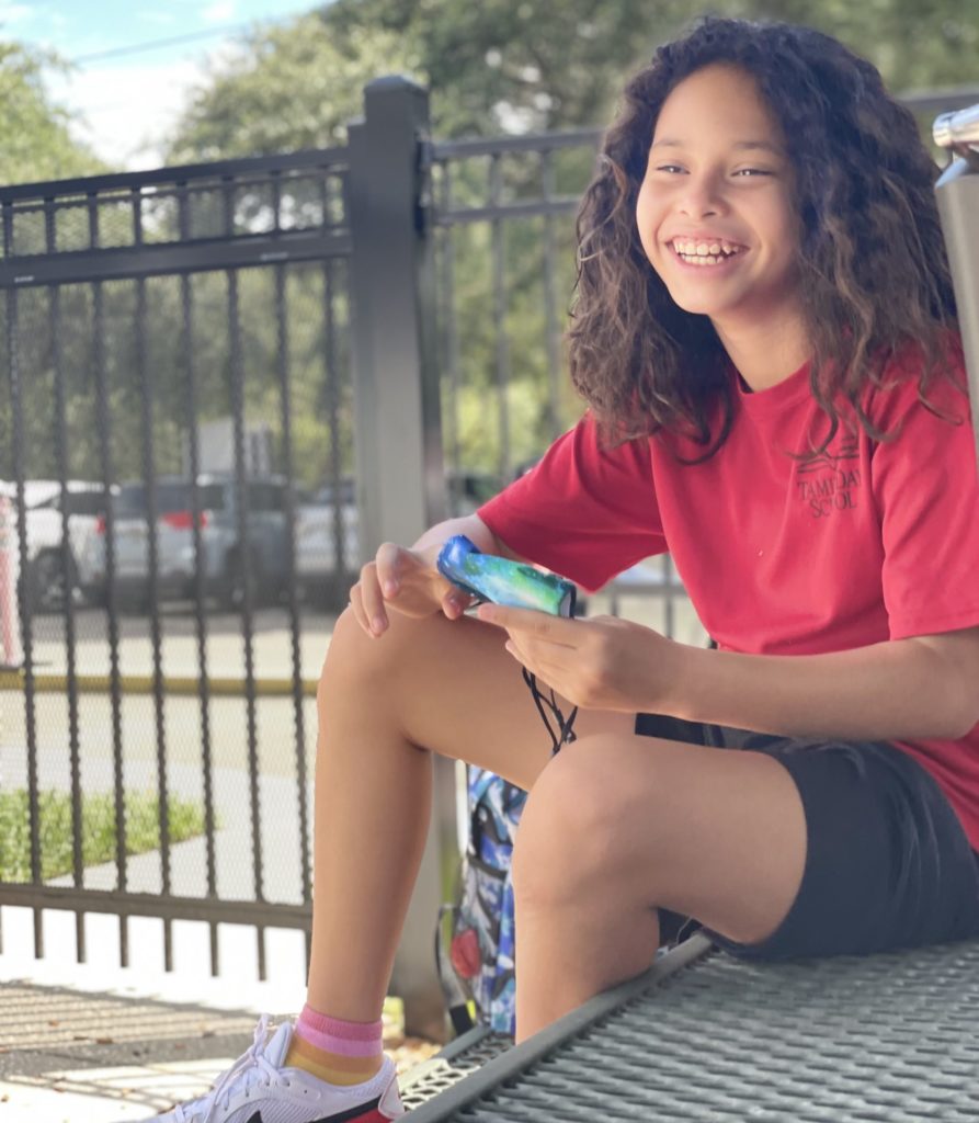 Female Student  sits outside and smiles during recess at Tampa Day School